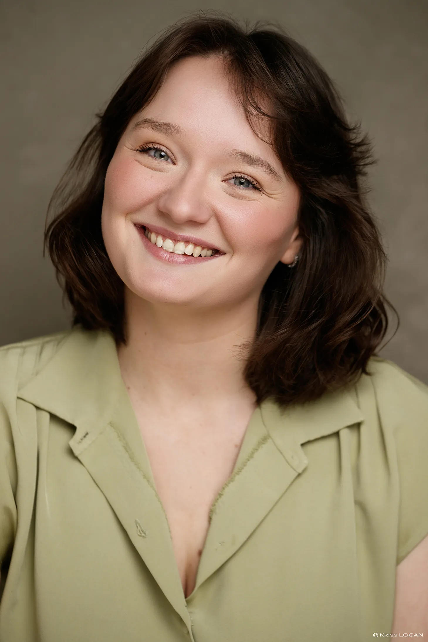 Portrait sourire ouvert, chemise vert pâle, fond sauge.