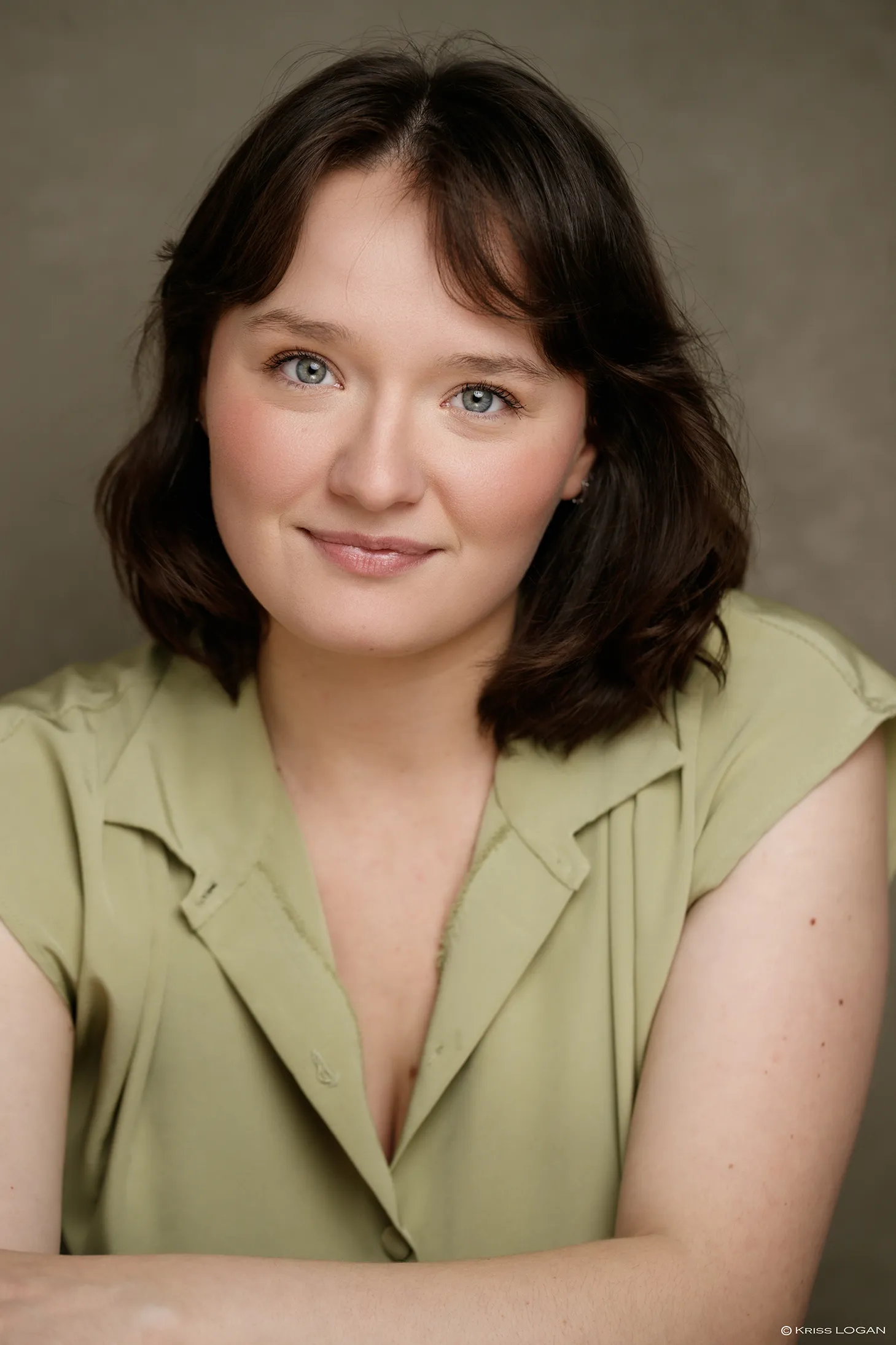 Portrait sourire doux, chemise vert pâle, fond sauge.