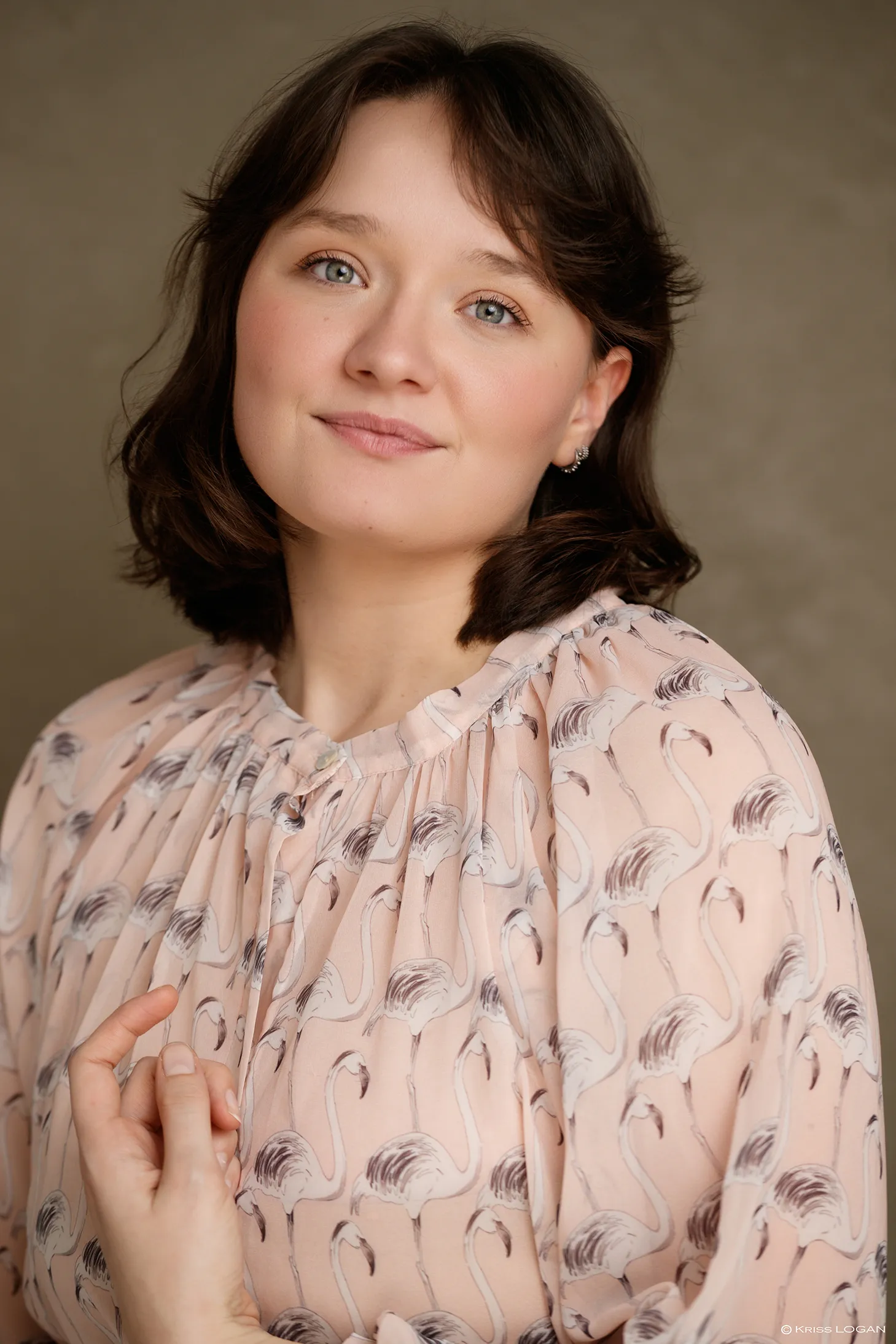 Portrait au sourire doux, pull col roulé bleu canard, fond gris-vert.