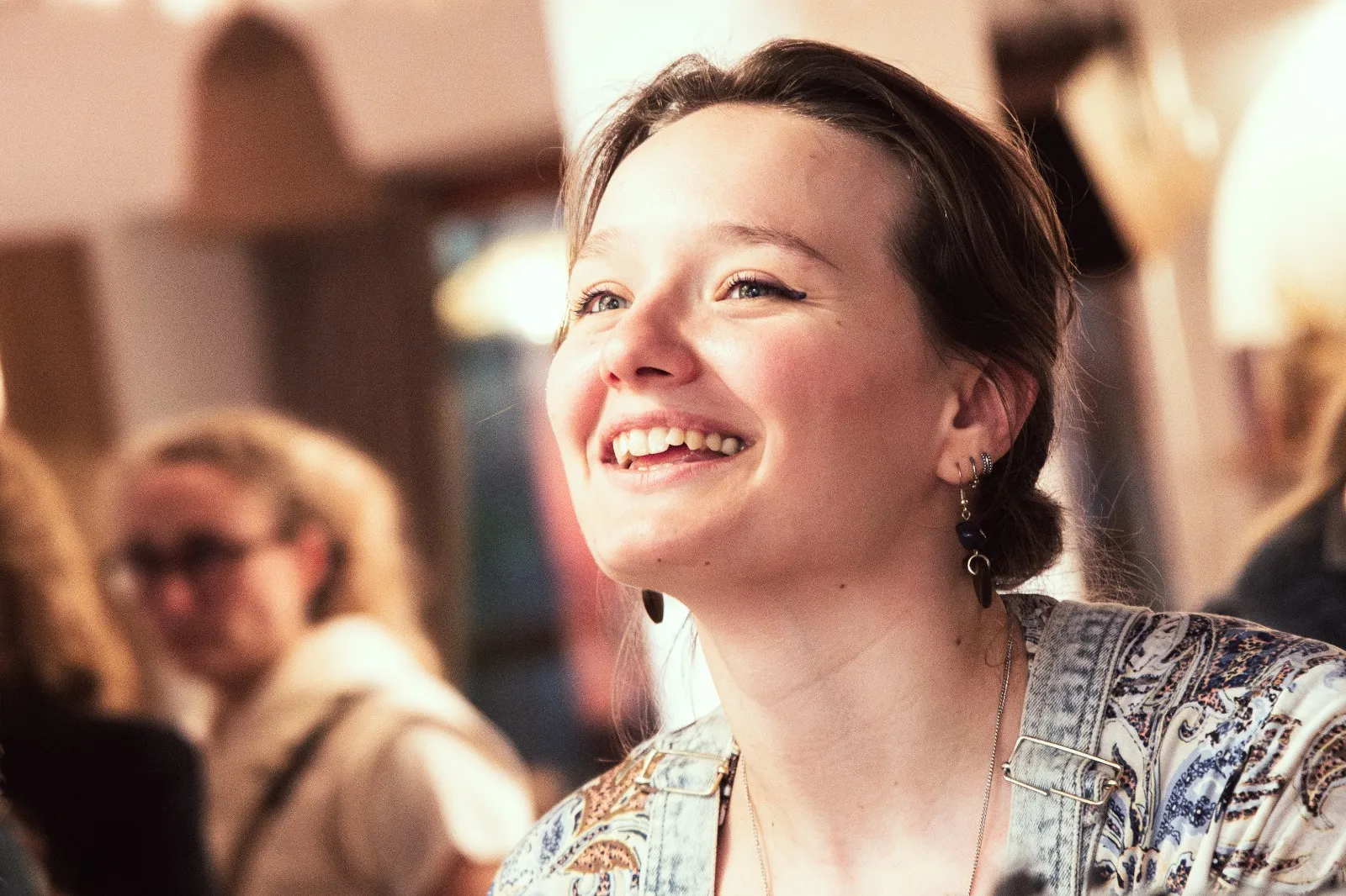 Portrait de Diane Burlot Henry, souriante, le regard levé, dans un intérieur chaleureux.