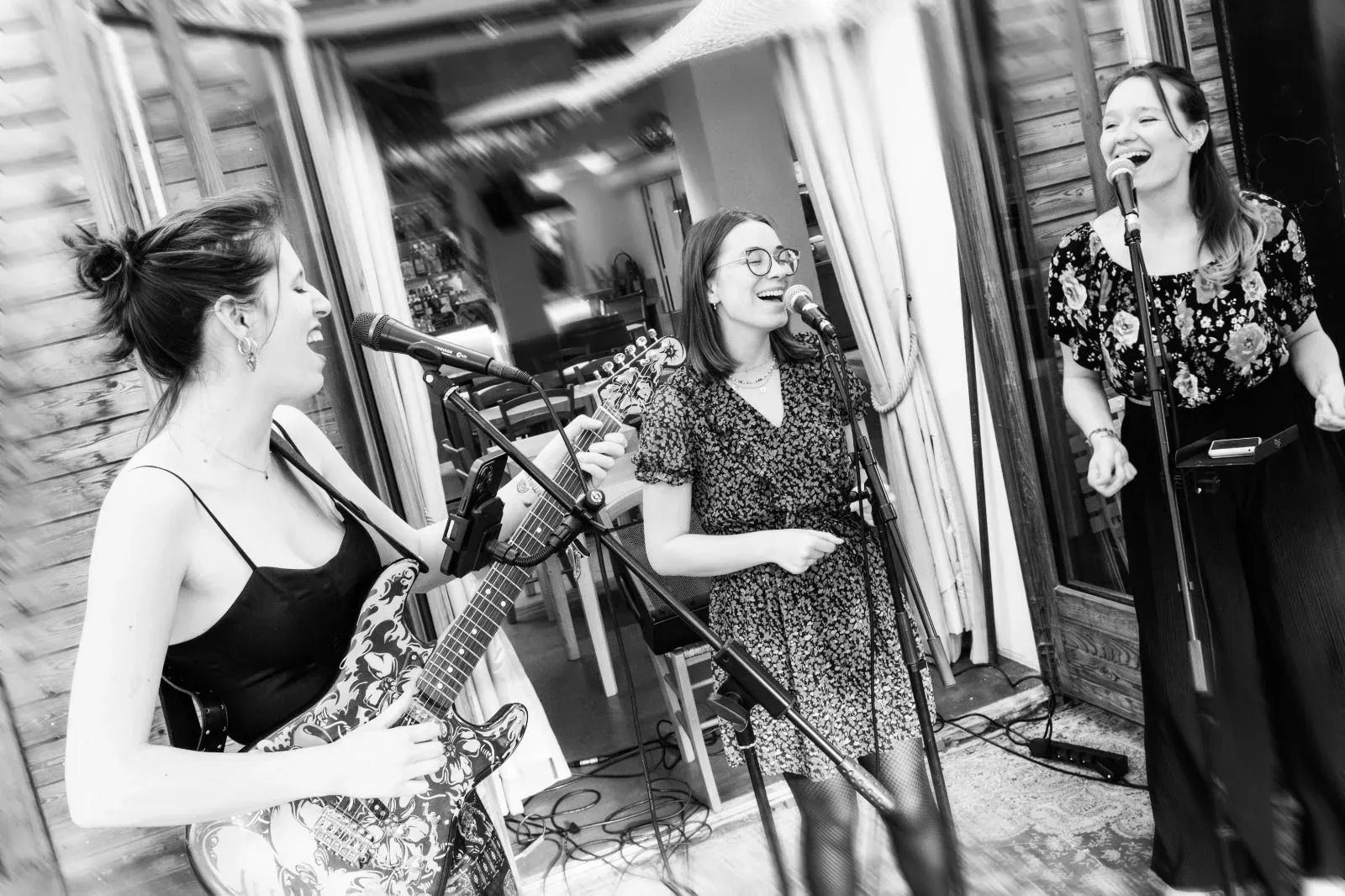 Trio singing outdoors, black and white photograph, one guitarist.