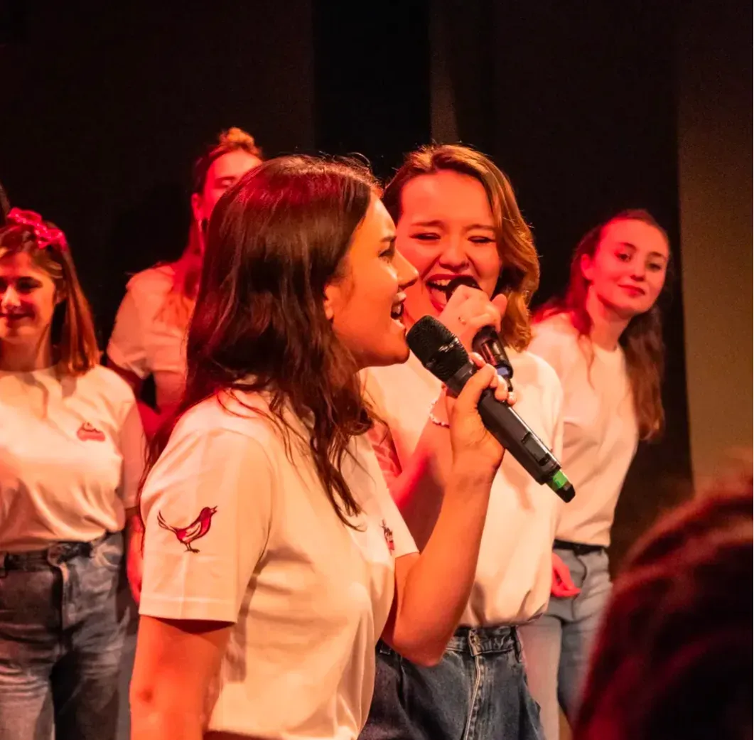 Choir on stage in white t-shirts, a soloist at the microphone.