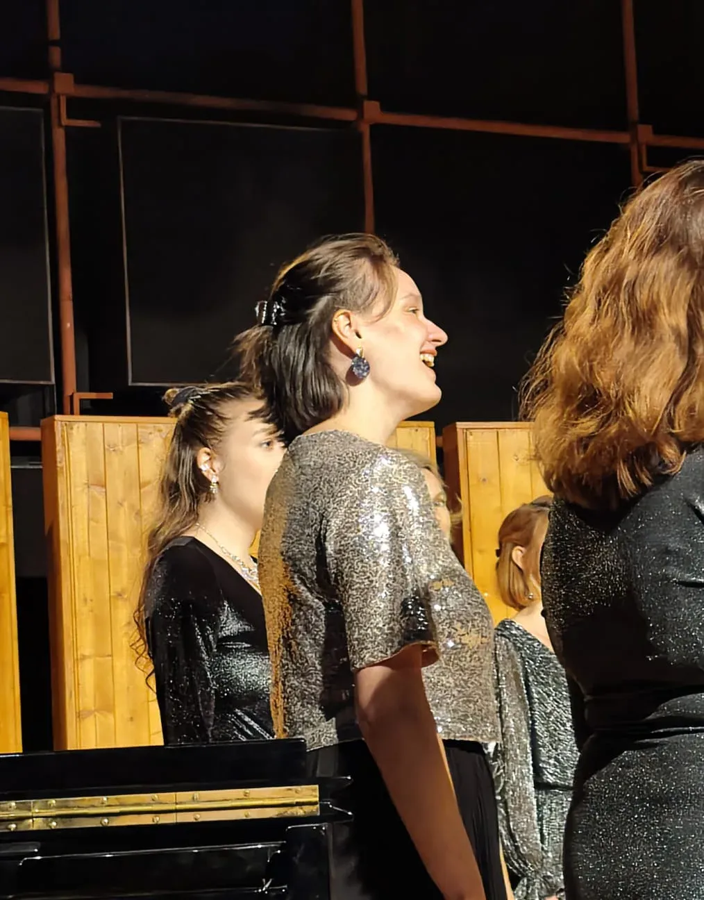 Diane in profile within a choir, silver sequined dress, on stage.
