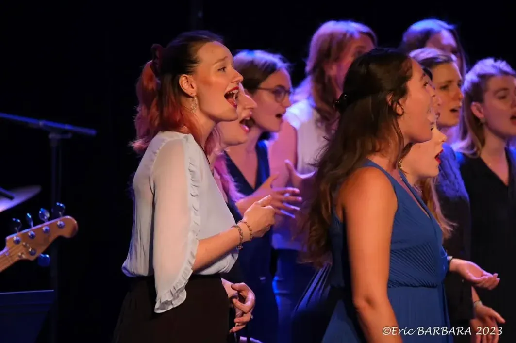 Choir in concert, a singer in the foreground, warm stage light.